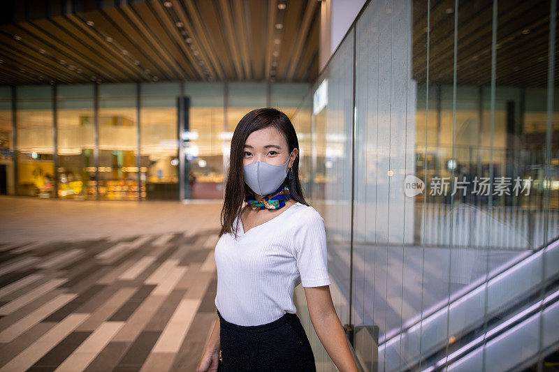 Portrait of female freelance worker standing in city, wearing face mask